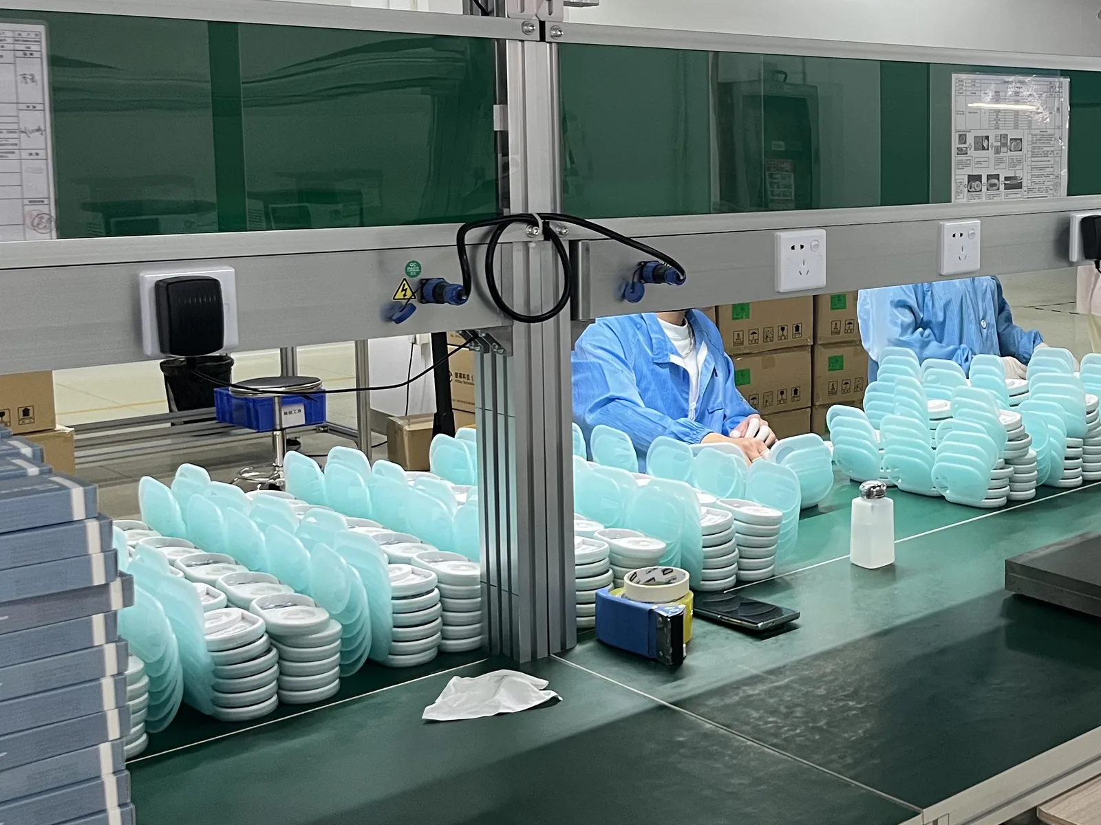 OnCorva sensor housings and mint-green storage cases stacked on the assembly bench at the Longgang production centre