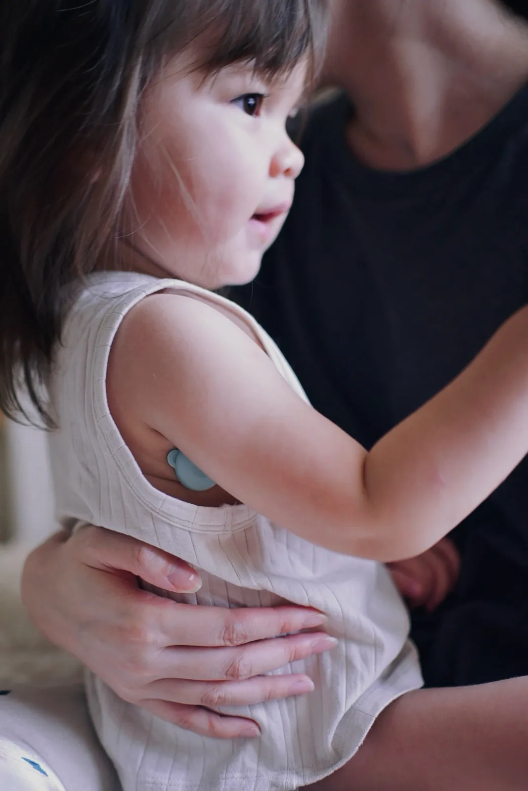 Toddler in a parent's arms wearing the 2g OnCorva sensor with a hypoallergenic patch